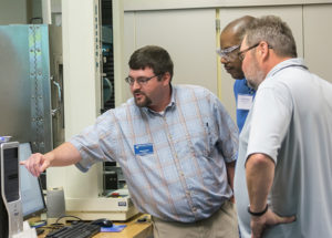 Adam C. Barilla, instructor of plastics and polymer technology at Penn College, demonstrates tensile testing to participants during the 19th annual Extrusion Seminar & Hands-On Workshop at the college’s Plastics Innovation & Resource Center.  (Photo by Tia G. La, student photographer)