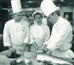 During preparation for the college’s first Visiting Chef dinner in 1992, students Ric Newton and Vanessa Buck study the technique of Visiting Chef Richard L. Kimble Jr.