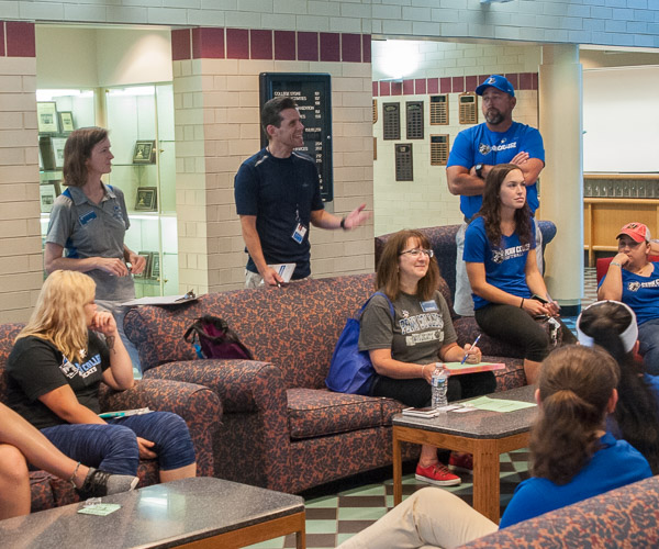 Tina M. Miller (standing at left) and Tom Speicher (standing at center) offer guidance to the student-athlete volunteers who would escort Little League teams throughout their time on campus.