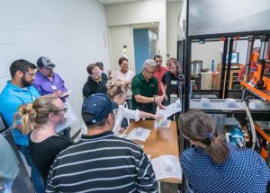 Mark Strachan (in green shirt), senior technology director for First Quality Packaging Solutions in West Palm Beach, Florida, and former chairman of the Society of Plastics Engineers Thermoforming Division, reviews results of a temperature change with participants at the Eighth Annual National Hands-On Thin-Gauge/Roll-Fed Thermoforming Workshop at Penn College’s Plastics Innovation & Resource Center.