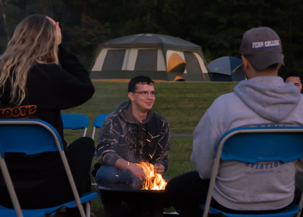 Army veteran Keenan A. Bayus, a software development and information management major from Waterford, teaches campers the fundamentals of building a fire.