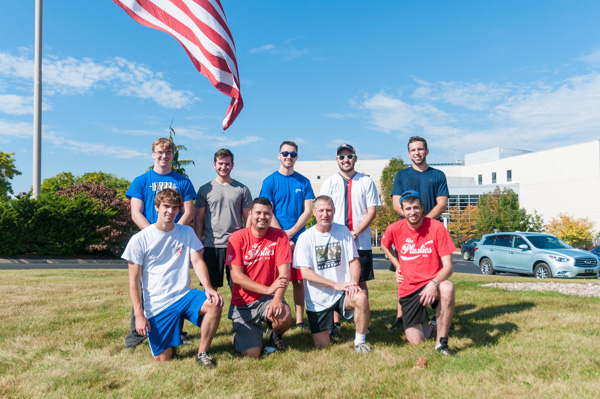 Participants in Saturday morning's Ultimate Frisbee matchup – including mentor Kirk M. Cantor (front row, second from right), professor of plastics and polymer technology – gather under Old Glory outside the SASC.