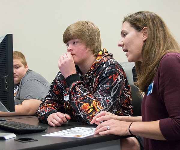 Alicia McNett, instructor of computer information technology, guides a high school student as he programs an Ozobot.