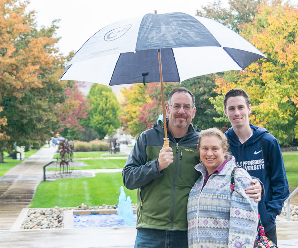 Pottstown residents Tom, Kim and Jason Francis pause during their soggy stroll for a portrait in campus exploration.