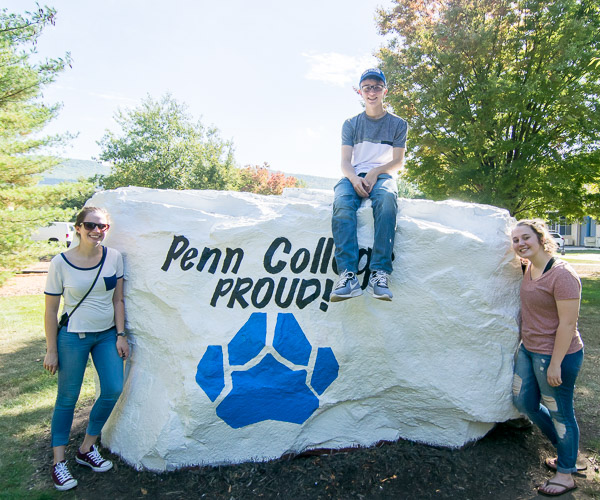 Plastics and polymer engineering technology student Jacob S. Virden, of Whiteford, Md., scales a campus landmark for a photo with his sisters.