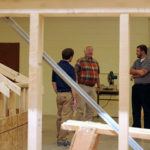 The students lead a tour of a carpentry lab, while picking their guest's brain about what college was like for him.