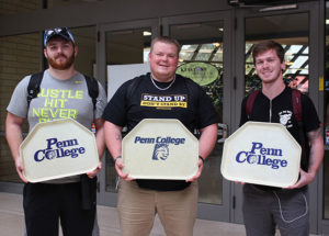 Penn College students, committed to helping their own through donations to the on-campus food pantry, hold “Vintage Wildcat Trays” used in the campaign.