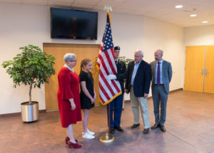 Placing the colors in the lobby of Penn College’s Student & Administrative Services Center – home to the Major General Fred F. Marty, USA Retired, Veterans and Military Resource Center – are (from left) President Davie Jane Gilmour; Teagan Marty, wearing her grandfather’s dog tags; ROTC Cadet Austin S. Weinrich, a residential construction technology and management: building construction technology concentration student from Jenkintown; state Sen. Gene Yaw, chair of the college’s board of directors; and Maj. Gen. Marty’s son, Patrick, vice president for college relations.
