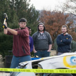 Supportive Sigma Pi fraternity brothers watch as a sledgehammer-wielding donor takes a healthy cut in the name of charitable destruction.