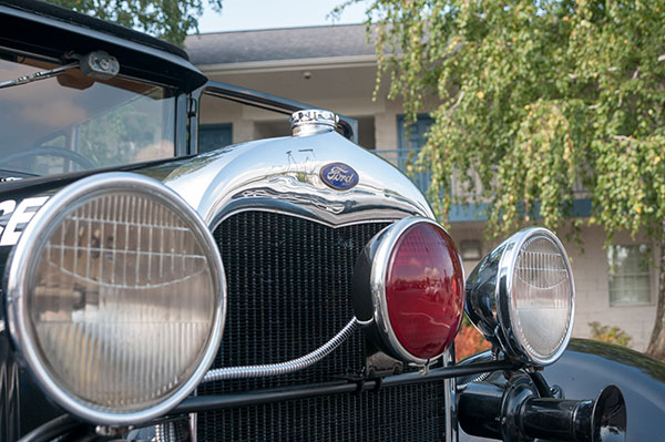 The Ford emblem and the Model A's front-mounted illumination catch some campus sunlight.
