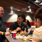 Chet Beaver (left), an Army veteran and financial aid specialist, shares his experiences with Brandon R. Belack (center), a civil engineering technology major from Halifax, and others during dinner.