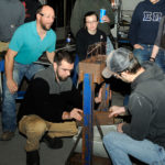 Instructor Colton (left) rises to better assess welding and fabrication engineering technology students Sean A. Moore (center), of York, and Michael J. Dippold II, of St. Marys, as they add more and more weight to their bridge. The pair's creation carried the Thursday afternoon leg of the annual competition, withstanding 494 pounds of pull.
