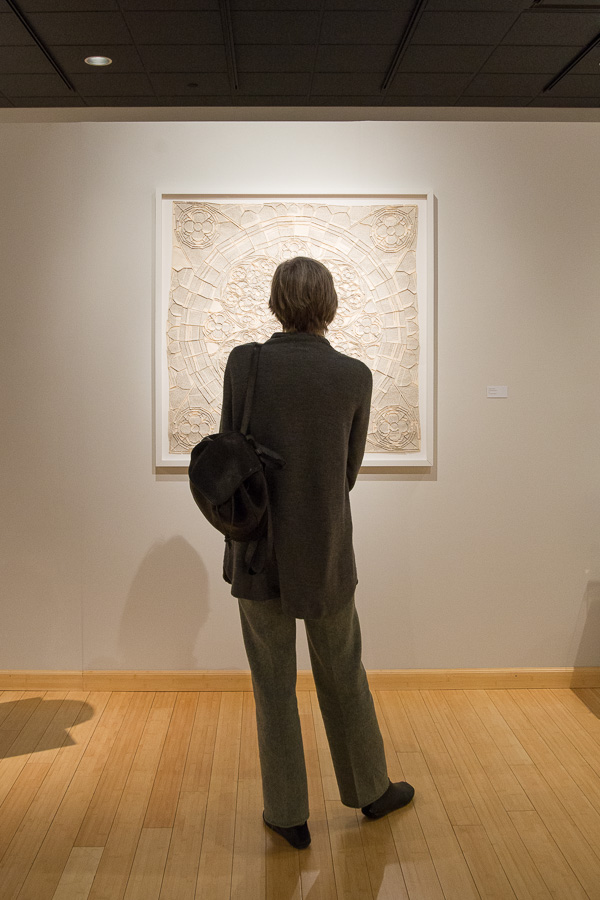 A gallery visitor contemplates “The Emersonian Rose,” a low relief sculpture by Greg Lookerse. 