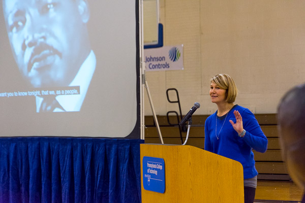 Standing alongside a photo of the day's guiding spirit, Katie L. Mackey, director of campus and community engagement at Penn College, welcomes participants.