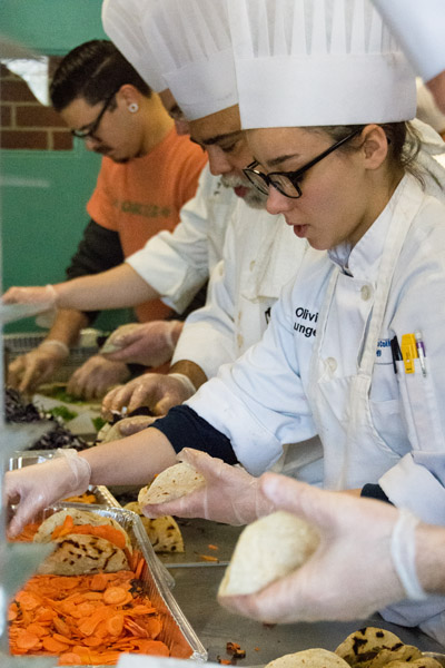 Alum Rich McGlynn (in orange) joins students in assembling 300 falafel taco samples.