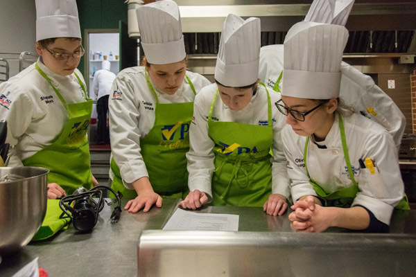 Students from team “Ninjas with Cupcakes” review the scoring criteria for the School Cooking Challenge. From left are Myers, Thomas, Wesneski, Geer and Lunger.