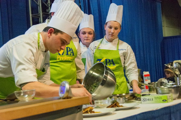 The Dream Team's Herceg begins plating the group's dessert. In background are teammates Smith, Mink and Callahan.
