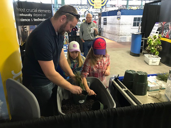 Justin Shelinski, laboratory assistant for horticulture, dishes the dirt with youngsters. Joining him in staffing the booth is Andrew Bartholomay, assistant professor of forestry.