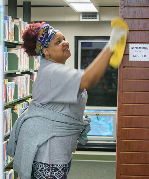 Business management major Tamaka Carter, of Williamsport, dusts library shelves.