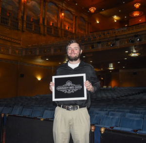 Austin L. Fulton, a graphic design major from Montoursville, holds his first-place design on-stage at the CAC.