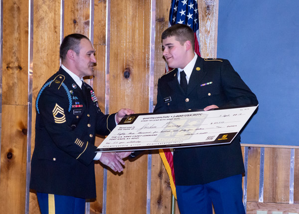 Holding an oversized scholarship check, Murray keeps one hand free for a congratulatory grip from Master Sgt. Steven Kowatch, senior military science instructor at Lock Haven University.