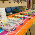 A table full of "Pride Swag" offers buttons, bracelets and other giveaways.
