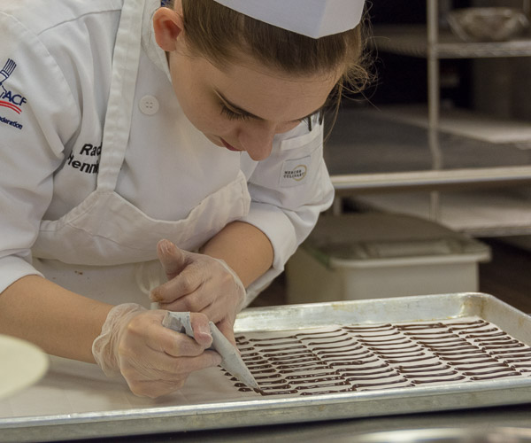 Rachel A. Henninger, a baking and pastry arts student from Bellefonte, forms chocolate “batons” that will top the dessert.