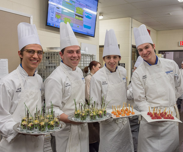 Culinary arts and systems students show off a variety of the hors d’oeuvres to be served during the pre-dinner reception: From left, Jacob W. Parobek, of Seltzer, and Paul J. Herceg, of Chalfont, show trays of “lump crab flutes”; David O. Spirache, of Reading, holds a plate of smoked salmon lollipops; and Dylan H. Therrien, of Reading, displays a plate of ahi tuna lollipops.