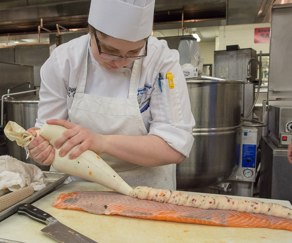 Magdalen C. Bennett, of Erie, pipes a sea scallop-lobster mousse onto a salmon filet for the first course.