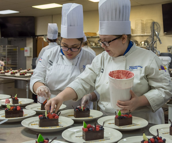 Maria E. Berrios (left), of Bethlehem, adjusts a garnish while Linea M. Kelley, of Turtlepoint, adds scoops of raspberry quenelle to the dessert.