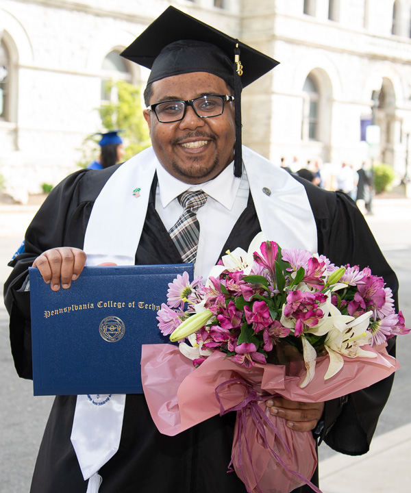 Yahya S. Rumaili holds the day's accessories (which includes a bachelor's degree in plastics and polymer engineering technology).