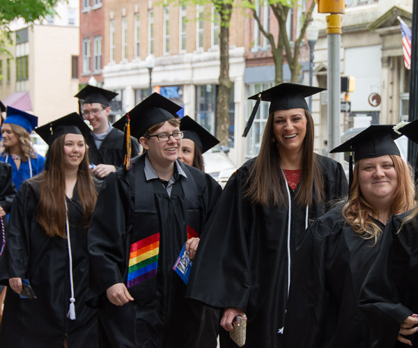 Camaraderie and easy smiles mark the walk of applied human services graduates to the Community Arts Center.