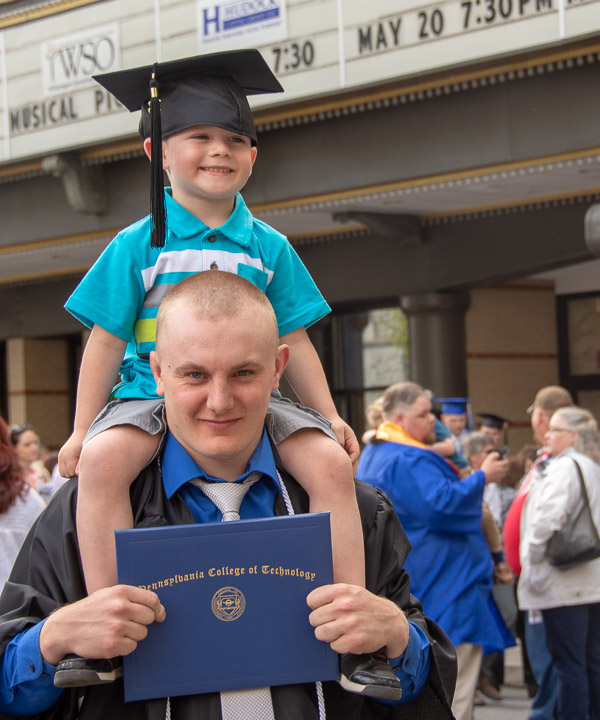 Codey M. Leh, a welding and fabrication engineering technology graduate from Frenchtown, N.J., hoists a young motivator on his shoulders.