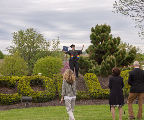 A proud graduate shows off the day’s treasures at the “PENN COLLEGE” shrubbery.