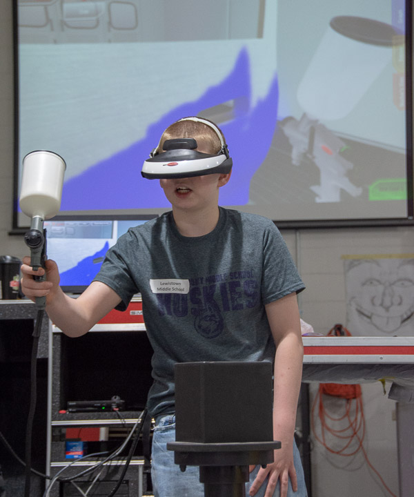 In the collision repair lab, a Lewistown Middle School student practices painting a vehicle using virtual-reality SIM Spray simulator. The session was led by Shaun D. Hack, instructor of collision repair and restoration.