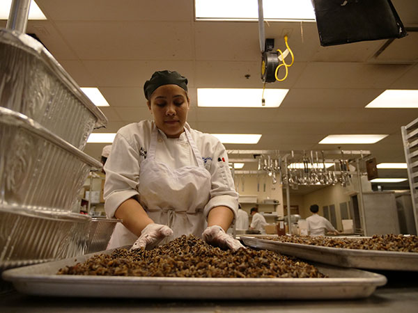 Alumna Alyssa Morales prepares tray after tray of wild rice.