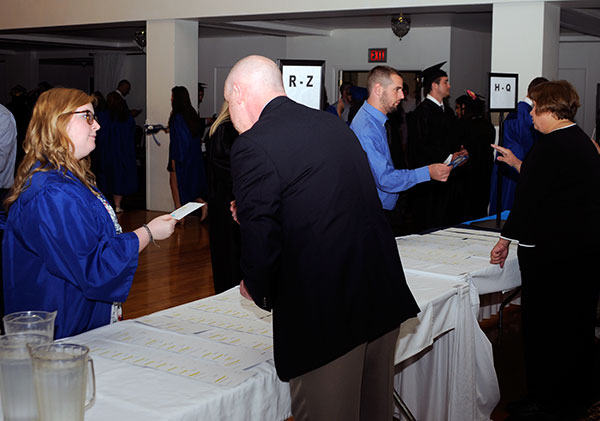 Graduates check in with Registrar's Office staff, including Philip G.Berry, external records evaluator, and Karen E. Wright, graduation assistant.