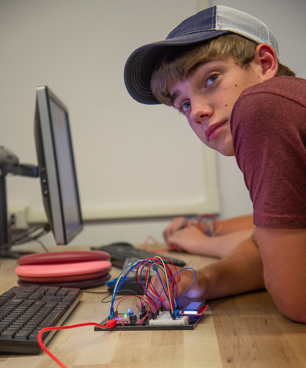 In an electronics and computer engineering technology lab, a camper listens intently to instruction. 