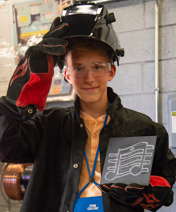 A musician learning to weld! A camper displays the artwork he sketched prior to applying a torch to it. 