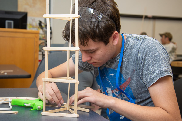 Fittingly clad in a NASA T-shirt, a camper crafts a Popsicle-stick skyscraper in engineering design technology.