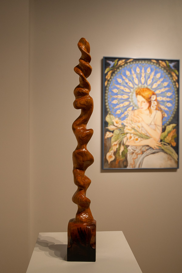 A red oak sculpture by Brandon Snyder stands near a watercolor by Cathy Frey. 