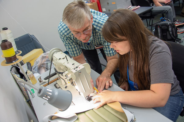 During the Automotive Restoration Camp, Paul J. Rose, laboratory assistant for automotive <br />
  <br />
  restoration technology, guides a camper through sewing a seam in her upholstery project.