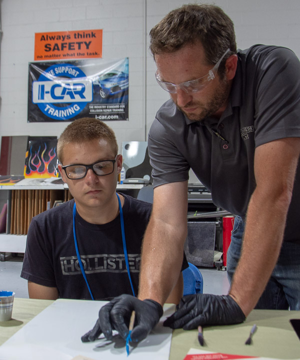 Shaun D. Hack, instructor of collision repair, gives each camper instruction in pinstriping.