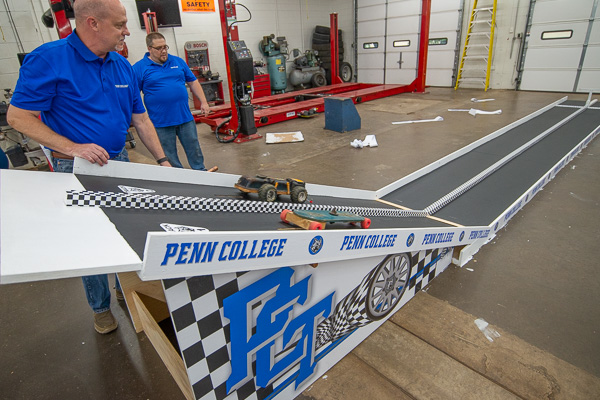 Walter V. Gower (left), assistant dean of transportation and natural resources technologies, and Daniels test the two-lane track ... which has sensors and lights at the finish line to indicate the winner of each heat.