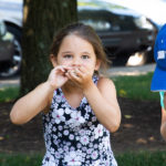 A focused camper tries to eat a stack of crackers as quickly as possible before running to tag her relay teammate.
