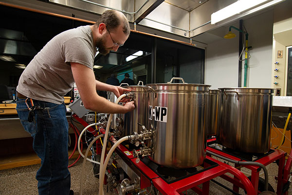 A brewing and fermentation science student works with the stainless steel brewing tanks in the industry-standard instructional space at Penn College. 