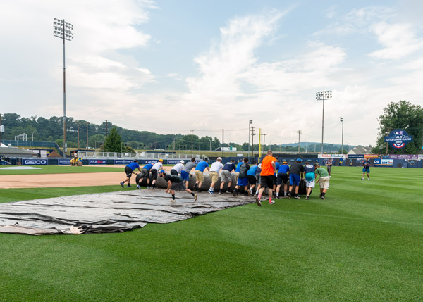 During the rollout, a volunteer retrieves a baseball snagged by the tarp during a Williamsport Crosscutters deployment.