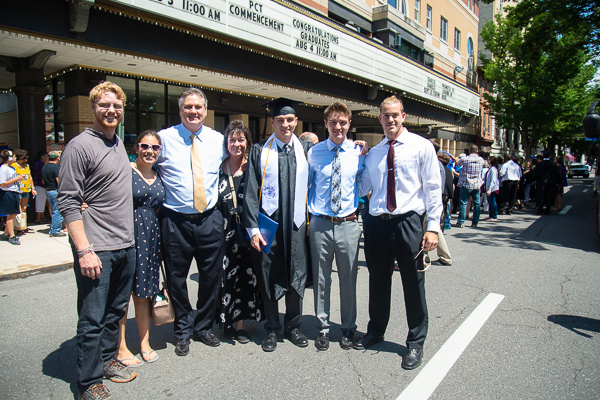 With the marquee heralding commencement activities in the background, physician assistant graduate Benjamin D. Meier, of Fleetwood, poses with his twin brother and other family members.