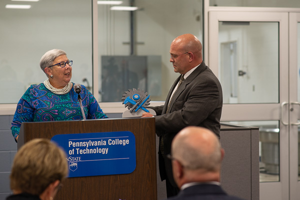 ... and presents the saw-blade-and-tools design to Welch, who also serves as chair of the Penn College Foundation Board of Directors. 