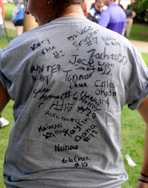 RA Kelsey L.  McKenrick, a dental hygiene major who escorted the West team from Honolulu, displays her autographed T-shirt. 